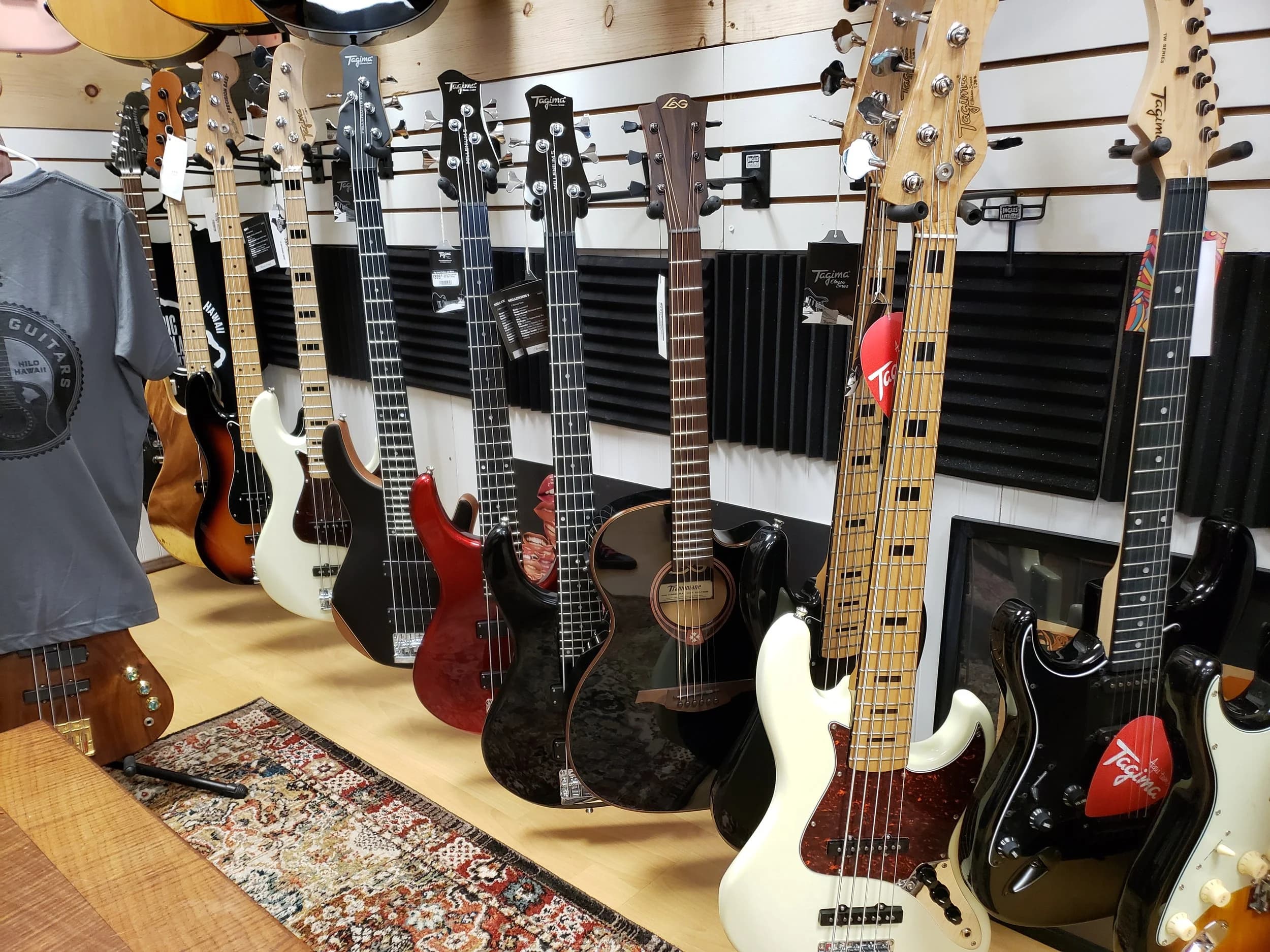 Basses and guitars lining the slatwall at Big Island Guitars in Hilo