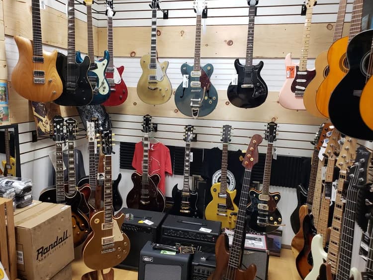 Used electric guitars and amps covering the wall at Big Island Guitars